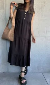 Vestido midi negro con escote en V, sin mangas, corte holgado y tres botones en la parte superior.