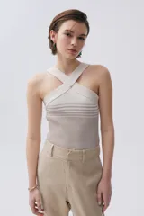 Top tejido color crudo con tiras cruzadas en el frente, confeccionado en algodón, acrílico y fibra metálica.