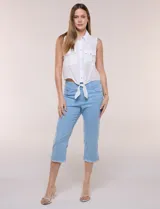 Capri blanco de corte ajustado, con tiro alto y pretina ancha elastizada tipo faja. Presenta bolsillos falsos al frente con remaches, piernas entalladas con pequeñas aberturas en los laterales y ruedo desflecado.