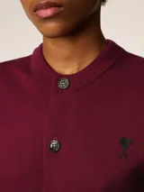 Cárdigan de lana color borgoña con cuello redondo, cierre frontal con botones y logo bordado en el pecho. Corte clásico.