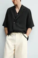 Camisa tipo kimono de corte relaxed fit, color celeste, confeccionada en tejido fluido de viscosa y lino. Presenta cuello con solapas de muesca, manga corta y cierre frontal cruzado con doble botonadura.