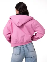 Chaqueta de lona color rosado con capucha ajustable, cierre frontal con cremallera y forro interior acolchado con diseño de diamantes. Presenta puños y bajo acanalados, bolsillos laterales y parche con el logo de la marca en el pecho.