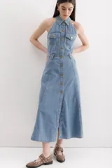 Vestido midi de denim celeste, con cuello camisero halter, botones dorados en el frente, bolsillos en el pecho y falda acampanada.