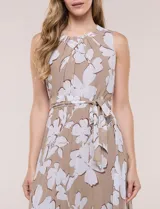 Vestido maxi sin mangas de gasa plisada, color beige con estampado floral blanco. Presenta escote redondo fruncido, falda evasé y lazo para anudar en la cintura.