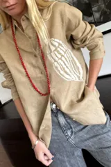 Camisa blanca de lino con bordado de pulpo azul en el pecho, de corte recto y manga larga.