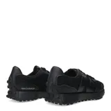 Championes urbanos New Balance modelo 327, color negro, confeccionados en una combinación de malla y material sintético. Presentan el logo 'N' característico en el lateral, cordones al tono y una suela de goma con relieve que se extiende hacia el talón.