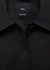 Chaqueta corta de corte recto con cuello camisero, cierre frontal de botones y dos bolsillos de parche laterales. Presenta mangas largas y forro interior.