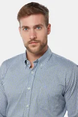 Camisa de manga larga con cuello abotonado y estampa a cuadros en tonos de azul y blanco. Presenta un bolsillo aplicado en el pecho con detalle de bordado y cierre frontal con botones.