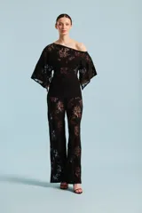 Mono largo de encaje negro, con diseño de hombros descubiertos, mangas amplias tipo kimono y pantalón de corte recto. Incluye un cinturón entallado del mismo tono.