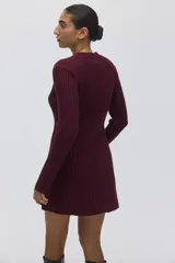 Vestido corto de punto acanalado color bordó, con cuello redondo, mangas largas y falda con leve vuelo. Presenta un diseño entallado con secciones de tejido menguado en la parte frontal y trasera.