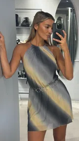 Vestido corto de escote halter con diseño plisado y estampado degradado en tonos gris y beige. Presenta un corte holgado y fluido, complementado con un cinturón de eslabones metálicos circulares.