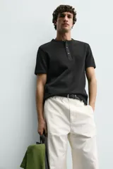 Camiseta de manga corta con cuello panadero y cierre frontal de tres botones. Presenta una textura acanalada y un corte regular fit.