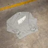 Buzo gris de corte oversize con cuello redondo y puños y cintura acanalados. Estampado frontal con la palabra "Midway" en blanco con borde negro. Tiene bolsillo tipo canguro.