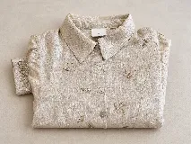 Camisa de lino color beige con bordados florales hechos a mano. Presenta cuello clásico, cierre frontal con botones nacarados y costuras frontales que definen la silueta.