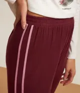 Conjunto de pijama largo de dos piezas: remera de algodón blanca con mangas largas y estampado de gatito, y pantalón de viscosa color borgoña con cintura elástica y puños ajustados.