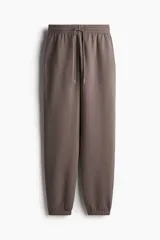 Pantalón deportivo de tiro alto confeccionado en felpa de mezcla de algodón con interior cepillado. Presenta cintura elástica con cordón de ajuste, bolsillos laterales al bies y puños elásticos en los bajos.