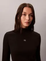 Top negro de manga larga con cuello tortuga, confeccionado en punto fino elástico de algodón BCI y lycra. Presenta un diseño ajustado de corte slim fit con un pequeño parche con el monograma de la marca en el centro del pecho.