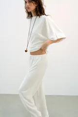 Top blanco de tejido rústico, con cuello redondo y mangas cortas amplias. Bajo recto.