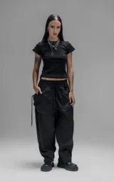 Pantalón de estilo utilitario y corte oversize, confeccionado en textil técnico liviano. Presenta cintura elástica con cordón ajustable, bolsillos laterales envolventes de gran tamaño con cordones y tancas de ajuste, y elásticos regulables en los tobillos.