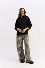 Camisa de algodón color blanco, de corte relajado y estilo western. Presenta detalle de tachas metálicas en la parte superior delantera y mangas largas con puños.