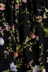 Vestido largo negro con estampado floreado, cuello mao, mangas globo cortas y falda escalonada con volados.