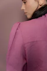 Blusa de lino color fucsia con cuello alto y volados frontales. Presenta mangas largas abullonadas y cierre frontal con botones a tono.