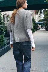 Jersey de punto color amarillo pálido, con cuello redondo y mangas cortas. Presenta un calce oversize y aberturas caladas en los laterales inferiores.