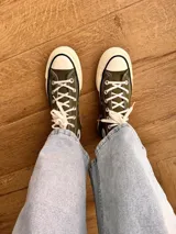 Zapatillas de lona color beige, tipo bota, con cordones marrones, puntera de goma y logo de peach engomado.