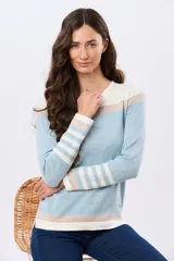 Buzo tejido de algodón con diseño rayado en tonos celeste, blanco, beige y rosado, de manga larga y calce relajado, con cuello redondo.