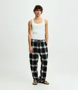 Pantalón de pijama de corte recto confeccionado en franela de algodón con estampado de cuadros en tonos blanco y negro. Presenta cintura elástica con cordón de ajuste para mayor comodidad.
