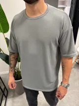 Remera de corte oversize confeccionada en tejido de punto con textura tipo waffle, cuello redondo y mangas cortas.
