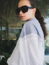 Blusa con cuello mao y mangas globo, confeccionada en algodón. La parte superior es de rayas azules y blancas, y la parte inferior es blanca con detalles de encaje.