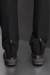 Pantalón de jogging negro confeccionado en tejido técnico ligero y elástico, corte slim fit, con cintura elástica ajustable con cordón, bolsillos laterales y trasero con cierre de cremallera, bandas reflectantes en las piernas y bajos ajustables con cremallera.