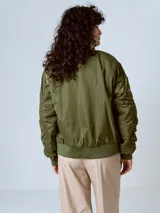 Campera estilo bomber acolchada, color verde militar, con hombros caídos y corte holgado. Presenta cierre frontal metálico y puños y cintura de elástico acanalado.