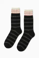 Medias color negro con diseño de franjas horizontales grises en damero y puño superior de color marfil con líneas rojas.