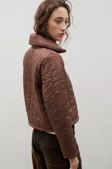 Campera crop acolchada color marrón, con cuello alto, cierre frontal y apliques de flores en el pecho. Presenta un diseño capitoneado y forro interior.