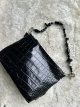Mini cartera de cuero con textura efecto cocodrilo, color negro, con correa corta de cuentas y abalorios negros.
