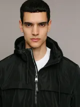 Campera ligera Calvin Klein de corte regular, confeccionada en tejido técnico resistente al viento y la llovizna. Presenta cierre frontal con cremallera, capucha ajustable con cordones, bolsillos laterales con cierre y puños elásticos.