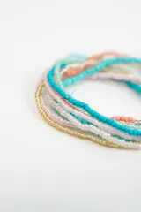Set de pulseras elásticas compuestas por múltiples hileras de cuentas de vidrio en tonos turquesa, coral, blanco y dorado.