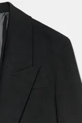 Blazer corto de corte recto con cuello de solapa, manga larga y hombreras. Presenta un diseño minimalista sin botones y forro interior a tono.