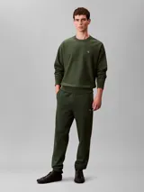 Pantalón jogger de felpa verde oscuro, con cintura elástica, bolsillos laterales y bajos ajustados en canalé. Incluye el monograma CK bordado en la pierna. Marca Calvin Klein.