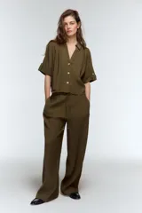 Pantalón de tiro alto con corte recto y pernera fluida. Cuenta con cintura elástica ajustable mediante cordones con detalles decorativos y bolsillos laterales.