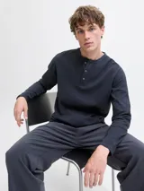 Remera de manga larga con cuello henley y cierre frontal con tres botones. Confeccionada en algodón orgánico, presenta un corte regular y diseño liso.