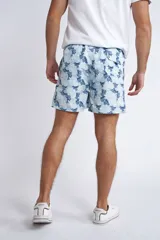 Short de baño con cintura elástica y cordón ajustable, confeccionado en tela ligera de secado rápido. Presenta un estampado botánico integral en tonos amarillos, blancos y azules, con dos bolsillos delanteros y uno posterior.