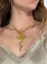 Collar dorado con dije en forma de serpiente y cordón fino color beige.