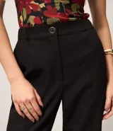 Pantalón femenino color verde oliva, confeccionado en crepé con modelo zanahoria, cintura alta y elástico para mayor comodidad. Posee cierre delantero con botón y bolsillos traseros.