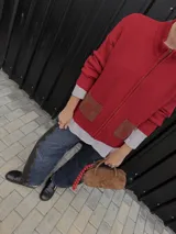 Campera tejida roja con cierre frontal, cuello alto y bolsillos con solapa.