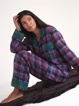 Pijama largo a cuadros de franela en tonos azul, rojo y verde, compuesto por una camisa de manga larga con solapas y botones frontales, y un pantalón largo de corte recto con puños y detalles en tartán verde.