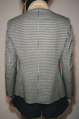 Blazer de corte estructurado con estampado de cuadros vichy en tonos neutros. Presenta cuello mao en color beige, cierre frontal con botones oscuros y bolsillos con solapa en el delantero.