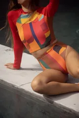 Conjunto de traje de baño compuesto por un top de mangas largas con estampado abstracto multicolor y una bombacha de tiro alto con laterales acanalados.